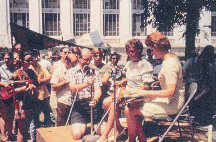 Judy performing at the 1970 Smithsonian Folk Life event in Washington DC with Jean Simmons. Howie Mitchell is setting up the mic.
